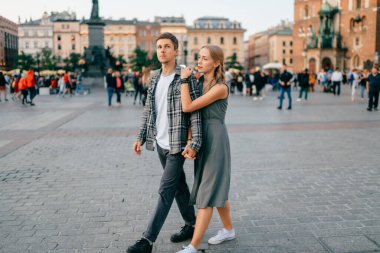 Krakow 'un ana meydanında gülümseyen ve yürüyen mutlu çift.)