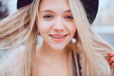 Komik gülümseyen, şık şapkalı sarışın kızın portresi. 