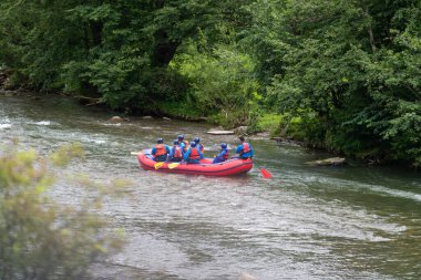 Nehirde rafting yapan bir grup kadın ve erkek. Aşırı su sporu