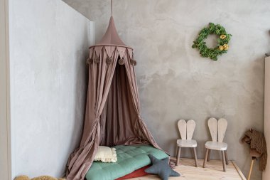 Perdeli çocuk yatağı, iki sandalye, duvarında bir çiçek çelengi, büyük bir tuzlama odası.