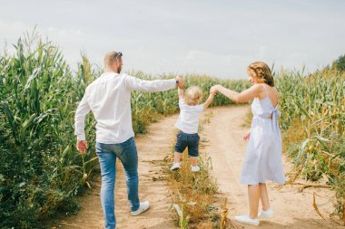 Açık mavi elbiseli genç, beyaz gömlekli, kısa siyah saçlı beyaz saçlı, beyaz pantolonlu, beyaz elbiseli güzel anne, küçük bebekleriyle çok eğleniyorlar.