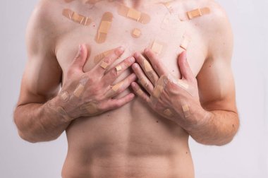 Vücudunda bir sürü yara bandı ve sargılı kafası beyaz arka planda izole edilmiş bir adam.