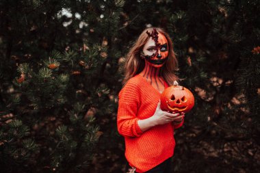 Cadılar Bayramı yüzlü genç sarışın kız dışarıda poz veriyor. Helloween kutlama konsepti.