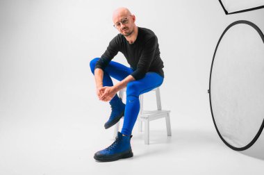 Beyaz arka planda merdivende oturan şık bir adam.