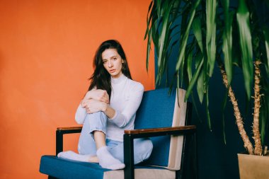 Yakışıklı beyaz modelin resmi koltukta oturur ve kameraya bakar.