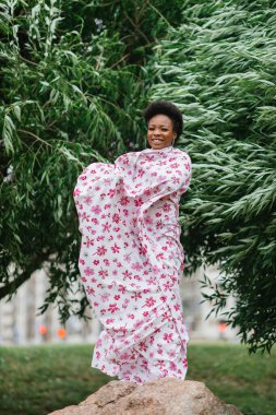 Afro-Amerikan genç modelin portresi. Geleneksel giyinmiş ve doğaya gülümseyen bir yüz.