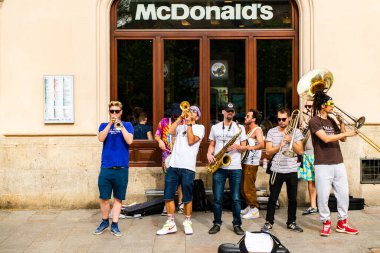 Krakow, Polonya - 26 Nisan 2019: McDonald 's' ın önünde müzik çalan bir grup müzisyenin sokak performansı.