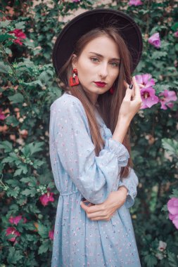 Güzel, genç bir manken. Şehvetli bir yüzü var. Çiçeklerle pusuya yatmış.