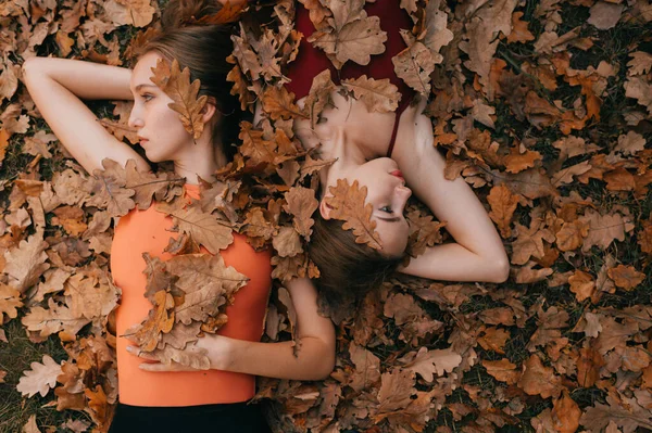 Duas Meninas Cobertas Com Folhas Outono Deitadas Chão Olhando Para — Fotografia de Stock