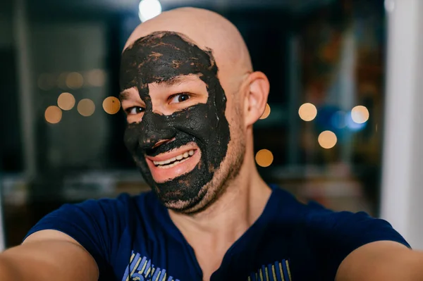 Man Met Houtskool Masker Zijn Gezicht Nemen Selfie Donkere Achtergrond — Stockfoto