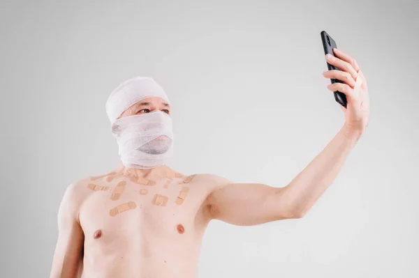 Injured Man Many Patches His Body Bandaged Head Holds Mobile — Stock Photo, Image