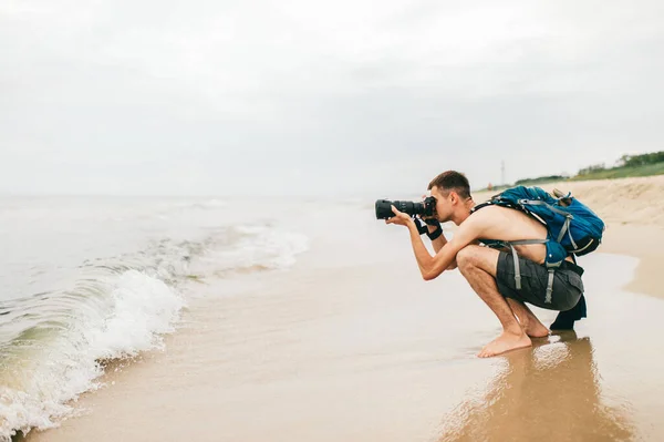 Człowiek Aparatem Fotograficznym Robi Zdjęcia Morza Mężczyzna Fotograf Siedzi Plaży — Zdjęcie stockowe