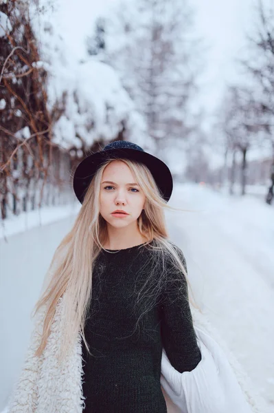 穿着外套头戴帽子的时髦漂亮金发姑娘站在街上篱笆边 — 图库照片