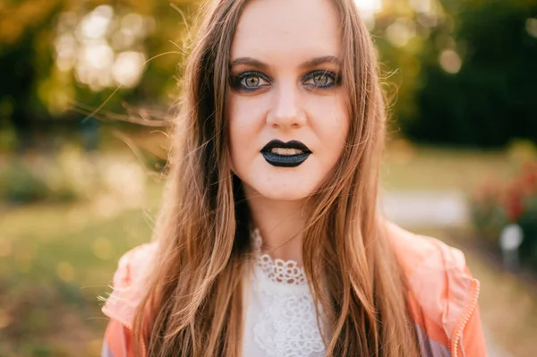 Smiling  girl with gothic make up and surpised face outdoor portrait in sunny park