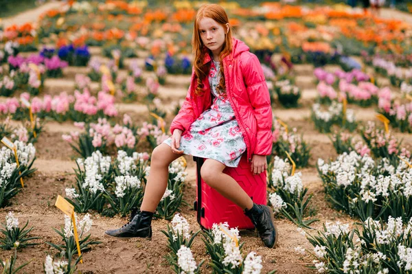 ファッション若いですモデルでピンクコートポーズのためにカメラ上の花の背景 — ストック写真