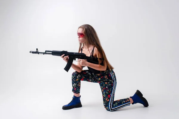 带着冲锋枪和白背交叉腿的未来派高加索女人 — 图库照片