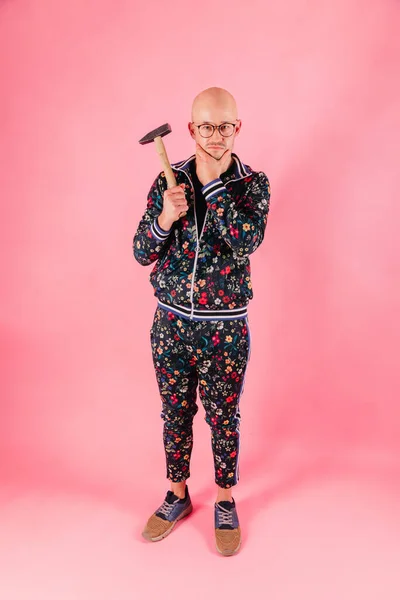 Funny fashionable man with hammer in his hand on pink background.