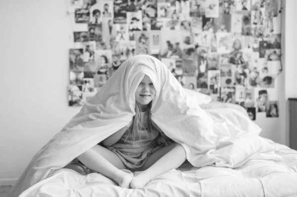 Menina Engraçada Sentada Cama Branca Segurando Cobertor Acima Sua Cabeça — Fotografia de Stock