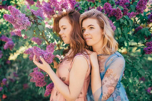 Två Vackra Flickor Med Blont Och Brunt Hår Lila Trädgård — Stockfoto