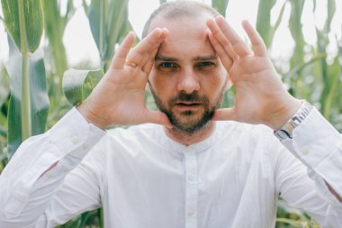 Beyaz gömlekli, kot pantolonlu ve beyaz çizmeli güzel beyaz bir adam mısır tarlasında yürüyüşe çıkıyor..