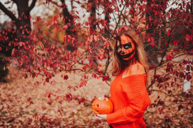 Cadılar Bayramı yüzlü genç sarışın kız dışarıda poz veriyor. Helloween kutlama konsepti.