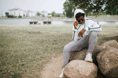 Sonbahar parkında kameraya poz veren kendine güvenen esmer adam portresi..