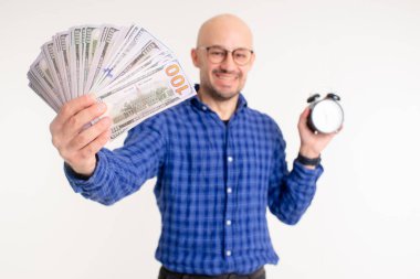 Mavi gömlekli, siyah pantolonlu ve mavi çoraplı yakışıklı beyaz adam zamanın beyaz arka planda izole edilmiş para olduğunu düşünüyor..