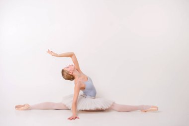 Sanat jimnastiği konsepti. Beyaz model, tam boy. Genç kız sanat jimnastiğiyle meşgul ve beyaz zeminde yatıyor.