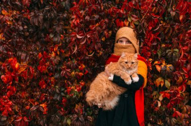 Gözleri bağlı, sırtüstü duran ve sonbahar parkında sarmaşık yaprakları üzerinde ellerinde şapkalar tutan yabancı bir çift..