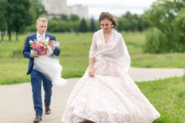 Damat duvak taşıyor ve akıllı telefonla konuşuyor. Düğün çifti dışarıda yürüyor..