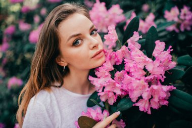 Çiçek açan ağacın arasında poz veren güzel bir kız.