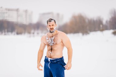 Karda sakallı, dışarıda poz veren güçlü, vahşi, çıplak bir adam.