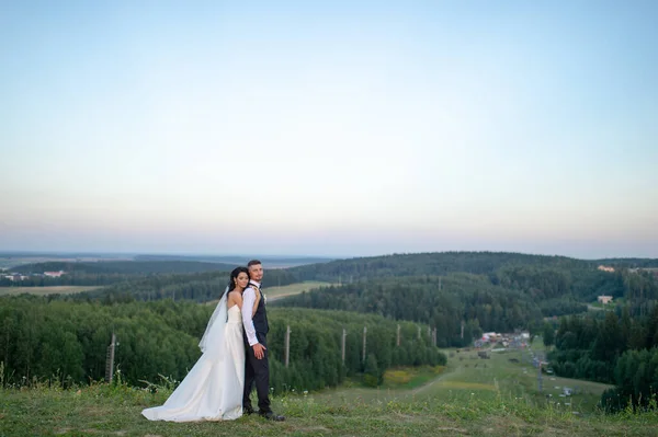 Прекрасная Невеста Обнимает Жениха Сзади Вершине Горы Вечером — стоковое фото