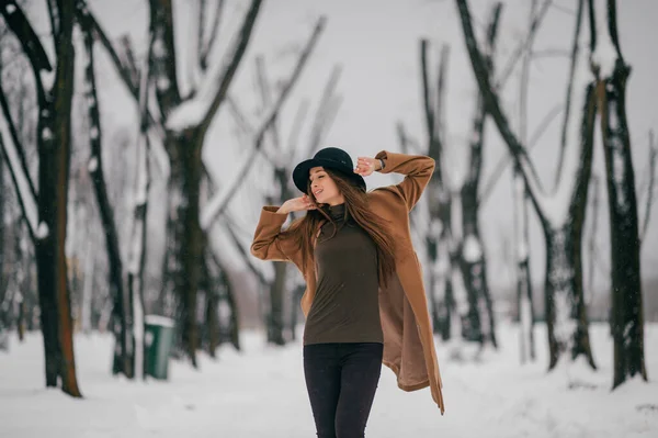 年轻快乐的姑娘穿着棕色的风衣站在冬树山谷里 — 图库照片