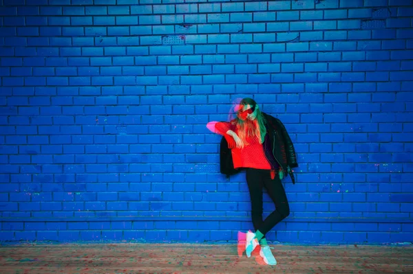 Double exposure fashion portrait of strange girl in stylish clothes posing over blue brick wall on background.