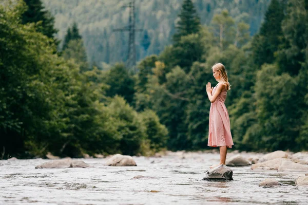 Young girl praying at nature, eyes closed