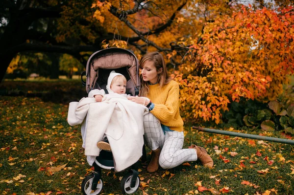 코카서스 엄마노란 블라우스 부츠는 가을에 유모차에서 그녀의 아기와 — 스톡 사진
