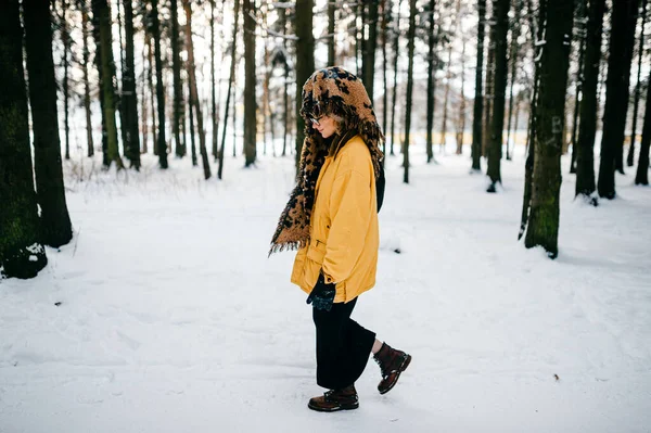 一个奇怪的年轻嬉皮士姑娘 戴着眼镜 头戴围巾 在雪地里散步 — 图库照片