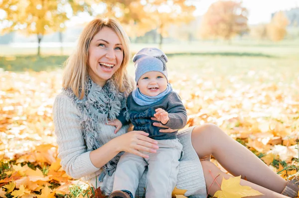 Matka Drží Svého Milého Syna Kolenou Podzimním Parku — Stock fotografie