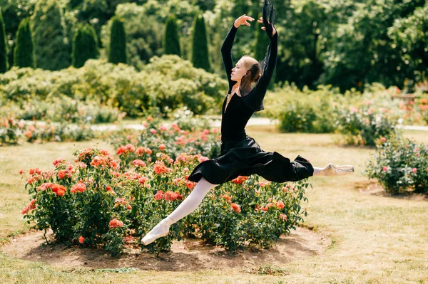 Jovem Bailarina Vestido Preto Saltando Entre Arbustos Rosa Parque — Fotografia de Stock