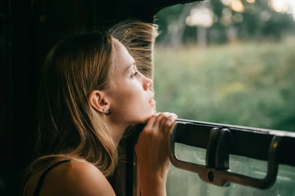 年轻美丽的金发姑娘从火车上向窗外看去 心情很好 在夏天驾驶火车的时候 漂亮的少年正享受着大自然的美丽 旅行概念 — 图库照片