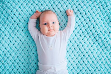 Mavi gözlü, sevimli, yeni doğmuş erkek bebek. İçeriden çekilmiş bir portresi var. Evde pijamada yatarken elleri ayrık tatlı bir çocuk. Duygusal yüzlü küçük çocuk kanepede dinleniyor.