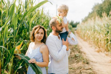 Açık mavi elbiseli genç, beyaz gömlekli, kısa siyah saçlı beyaz saçlı, beyaz pantolonlu, beyaz elbiseli güzel anne, küçük bebekleriyle çok eğleniyorlar.