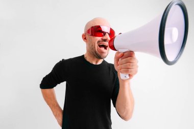 Kırmızı güneş gözlüklü kel adam hoparlörden beyaz arka plana bağırıyor. Takım motivasyonu kavramı.