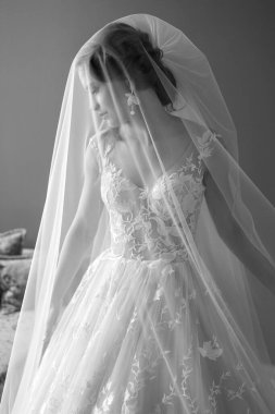 Gelinlik giymiş güzel gelinin siyah beyaz portresi dokunur ve duvağını otel odasına atar..