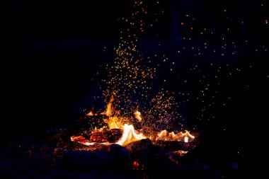 Geceleri odun yakmak. Dağlardaki turistik kamplarda kamp ateşi. Alevler soyut arka planda kıvılcımlar saçıyor. Dışarıda ızgara yapıyorum. Cehennem ateşi elementi. Yakıt, güç ve enerji