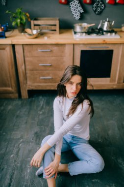 Şehvetli bir yüzü, mutfakta poz veren uzun siyah saçları olan sevimli genç bir manken. İç mekan hayat tarzı, neşeli, şefkatli, İspanyol görünümlü ve kameraya bakan kahverengi gözlü bir kızın portresi. 