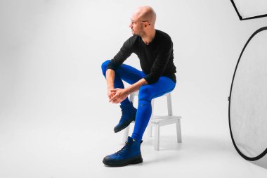 Beyaz arka planda merdivende oturan şık bir adam.