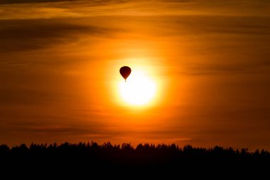 Gökyüzündeki spor olayı. Gün batımında balon uçuşu. Doğada güneş ışığıyla sakin, renkli romantik bir akşam. Yazın alacakaranlık silueti. Ufuktaki balonun yakın görüntüsü. Uzun odak uzaklığı.