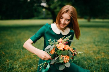 Bir buket yaz çiçeğiyle genç mutlu kızıl saçlı kız doğada yeşil elbiseli iç huzurun tadını çıkarıyor. Harikalar Diyarı Parkı 'nda oynayan küçük çocuk. Açık havada güzel bir kadın portresi. Güzel gülen surat..